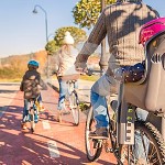 famiglia-con-i-bambini-che-guidano-le-biciclette-nella-natura-49573769